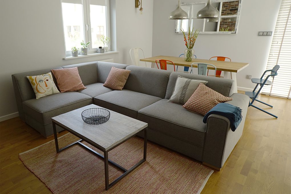 szara sofa w salonie, kącik jadalny w salonie, kolorowe krzesła do jadalni