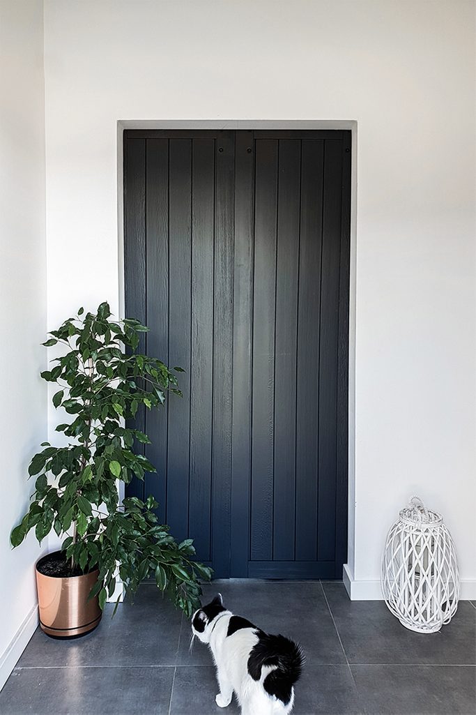 antracytowe drzwi drewniane w przedsionku, rozsuwane drzwi drewniane, drzwi wewnętrzne w kolorze antracytu, antracytowe drzwi w przedsionku, duże kwiaty w przedsionku