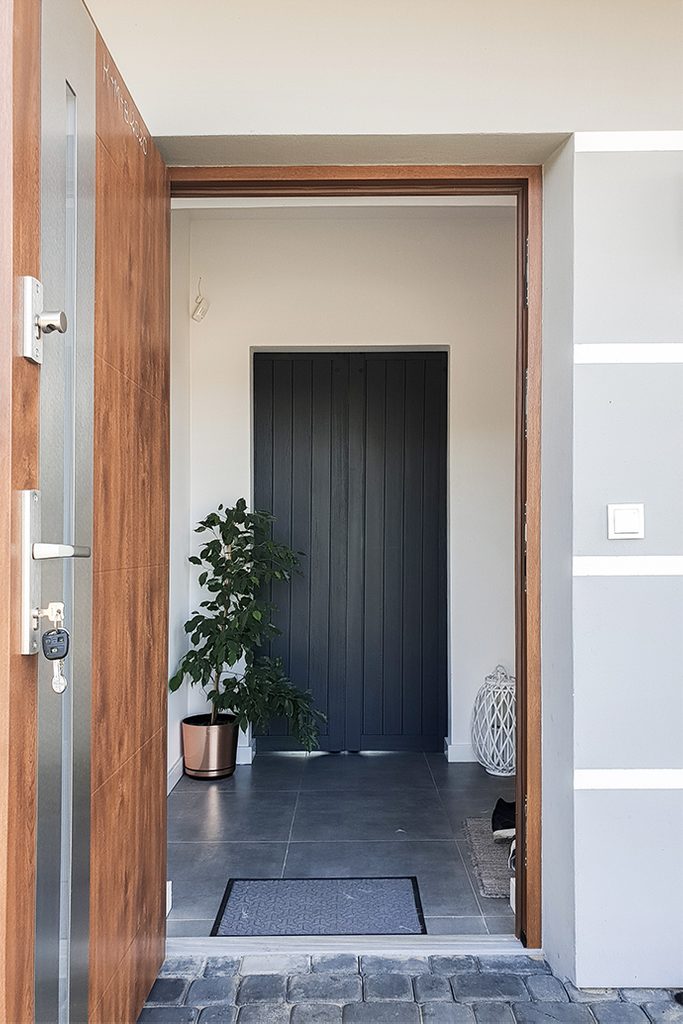 antracytowe drzwi drewniane w przedsionku, rozsuwane drzwi drewniane, drzwi wewnętrzne w kolorze antracytu, antracytowe drzwi w przedsionku, duże kwiaty w przedsionku