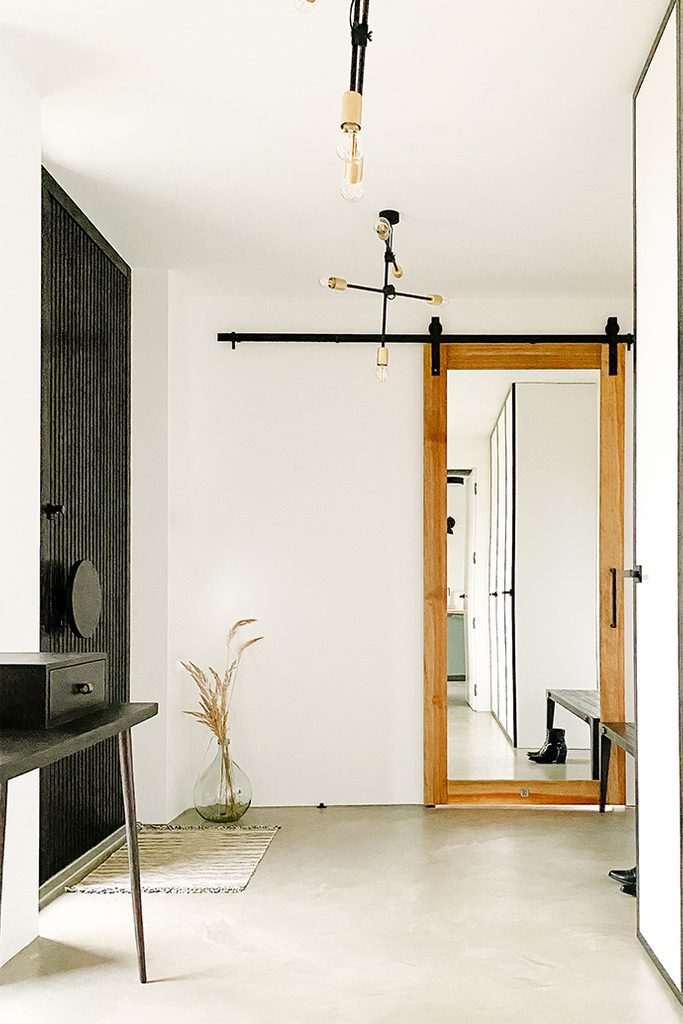 Industrialna lampa, czarny minimalistyczny stolik i drzwi przesuwne z lustrem w wiatrołapie