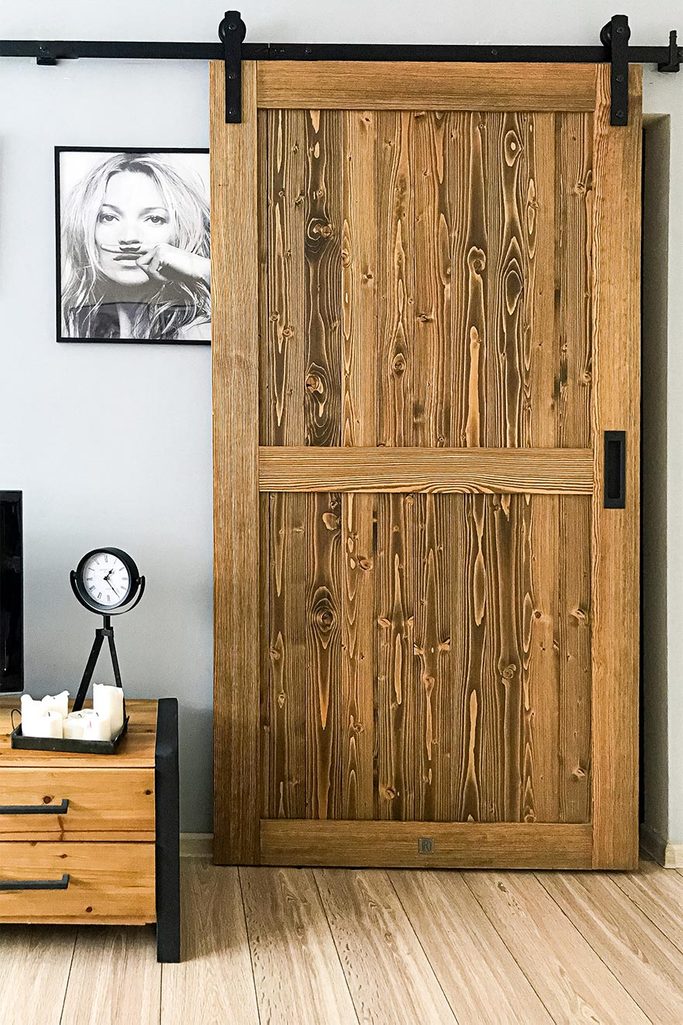Drewniane drzwi zamontowane na czarnym systemie przesuwnym