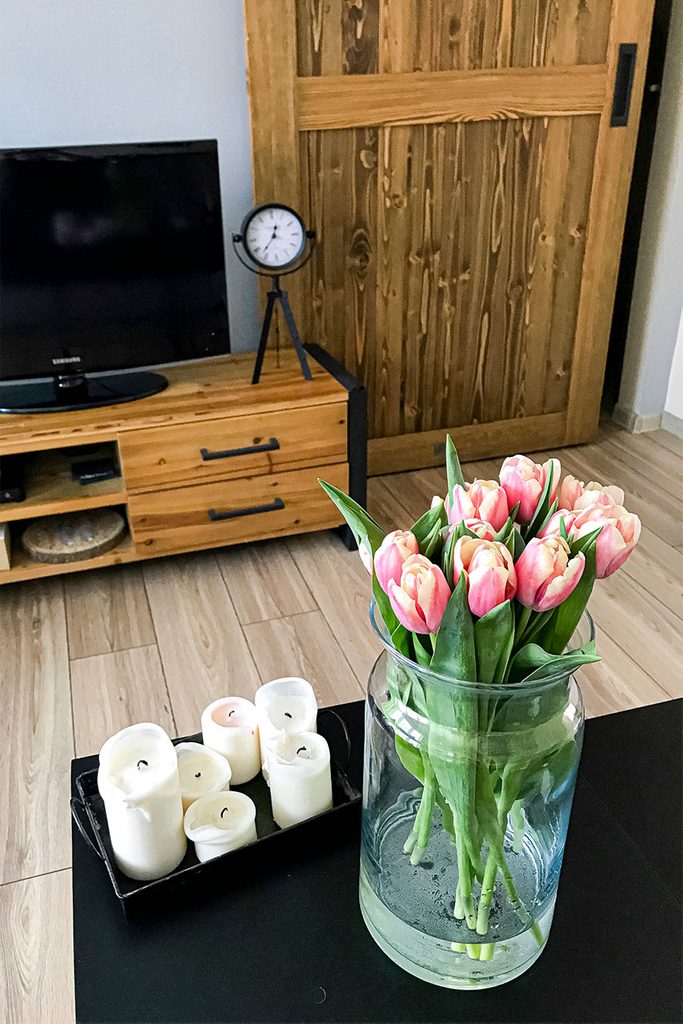 Bukiet tulipanów na tle drewnianych drzwi i drewniane szafki z telewizorem