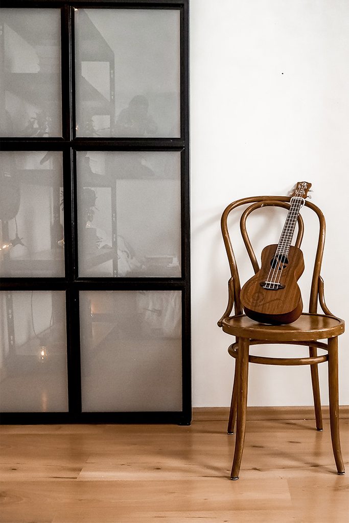mała gitara na giętym krześle w stylu vintage obok drzwi ze szkłem