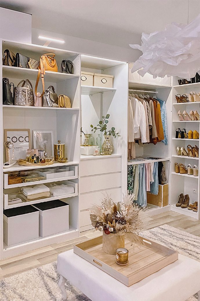 Buty, ubrania i torebki ułożone na białych półkach i regałach w aranżacji garderoby