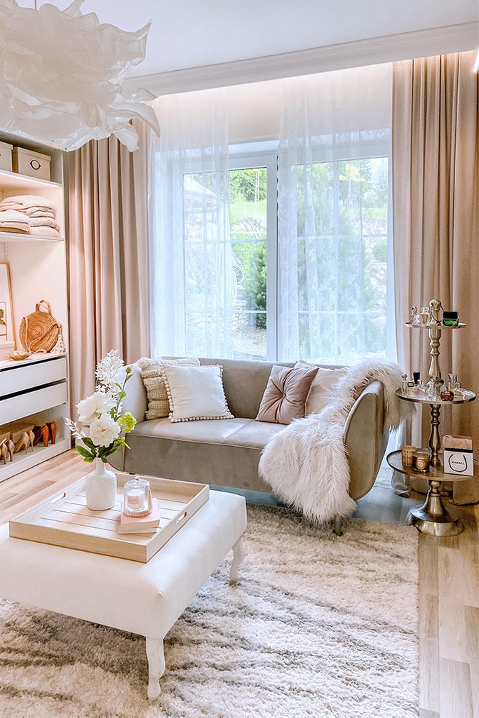 Białe siedzisko i szara sofa w jasnej aranżacji garderoby