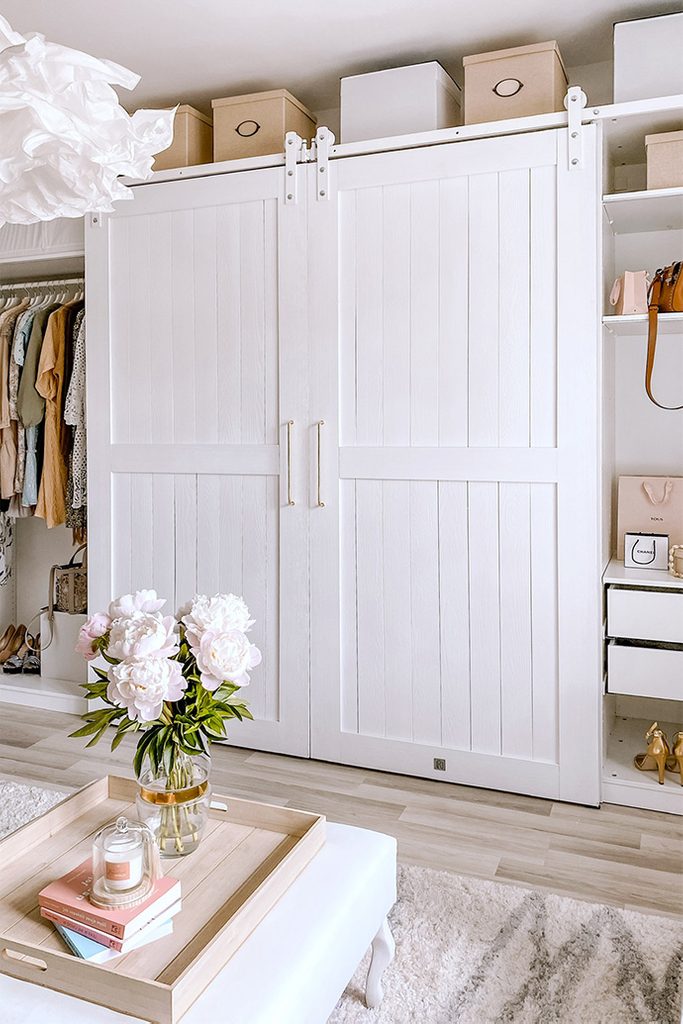 Duże białe drzwi dwuskrzydłowe na białym systemie przesuwnym w aranżacji garderoby