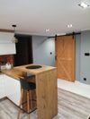 Drewniane drzwi przesuwne do spiżarni w nowoczesnej jasnej kuchni