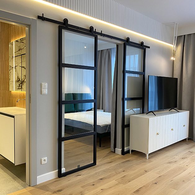 Industrialne podwójne drzwi przesuwne odzielające sypialnię od salonu w nowoczesnym mieszkaniu