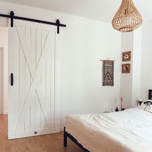 białe drzwi przesuwne obok dużego łóżka w sypialni
