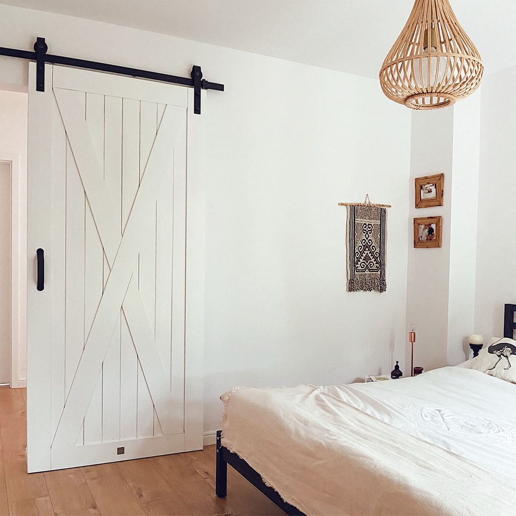 białe drzwi przesuwne obok dużego łóżka w sypialni