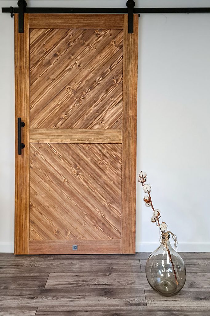 drewniane drzwi przesuwne na białej ścianie w skandynawskim wnętrzu