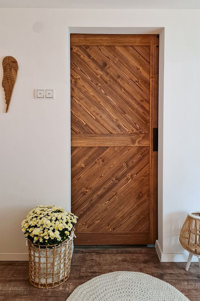 drewniane drzwi przesuwne zamykające wejście do sypialni w stylu skandynawskim