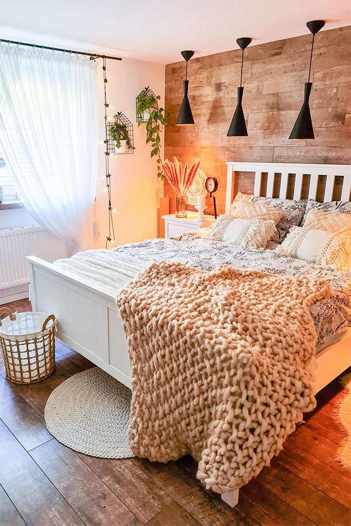 ozdobne poduszki i pled na białym łózku w skandynawskiej sypialni