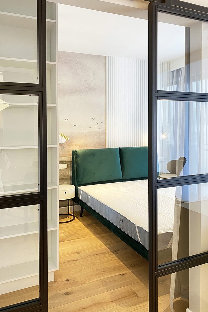 metalowe drzwi przesuwne ze szkłem w wejściu do sypialni nowoczesnego mieszkania