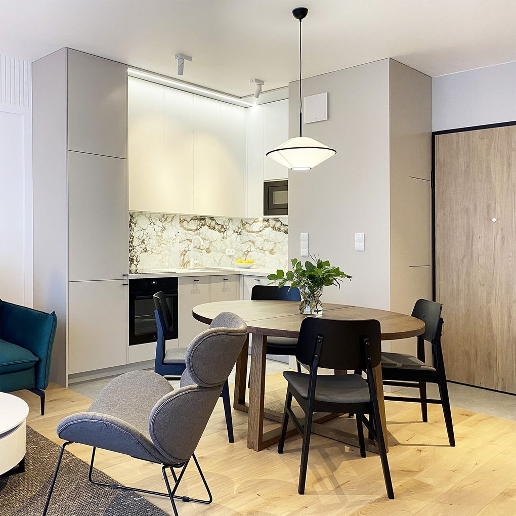 stół jadalniany w kolorze orzecha, czarne krzesła na tle jasnej zabudowy kuchennej w nowoczesnym mieszkaniu