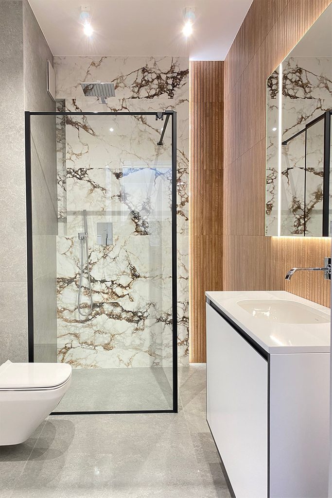 minimalistyczna zabudowa prysznicowa przy ścianie zdobionej motywem kamienia w nowoczesnej łazience