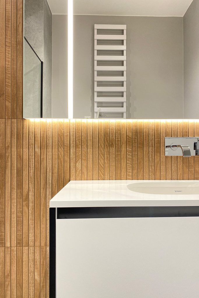 nowoczesna łazienka z białą armaturą i płytkami w kolorze drewna