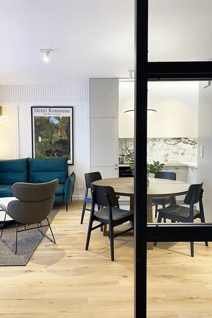 widok na salon połączony z jadalnią i aneksem kuchennym w nowoczesnym mieszkaniu