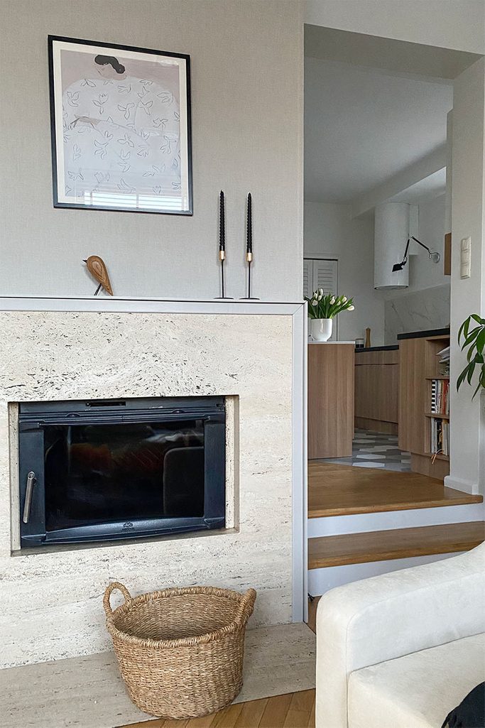minimalistyczne dekoracje na kominku na tle szarej ściany w salonie otwartym na kuchnię