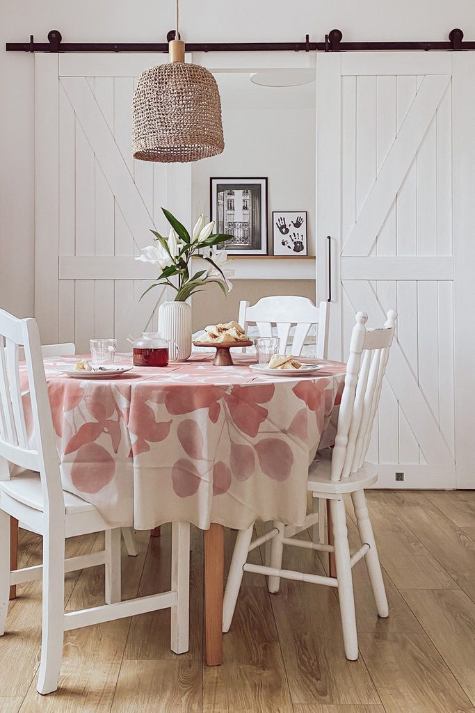 okrągły stół jadalniany, białe krzesła, podwójne drzwi przesuwne do sypialni