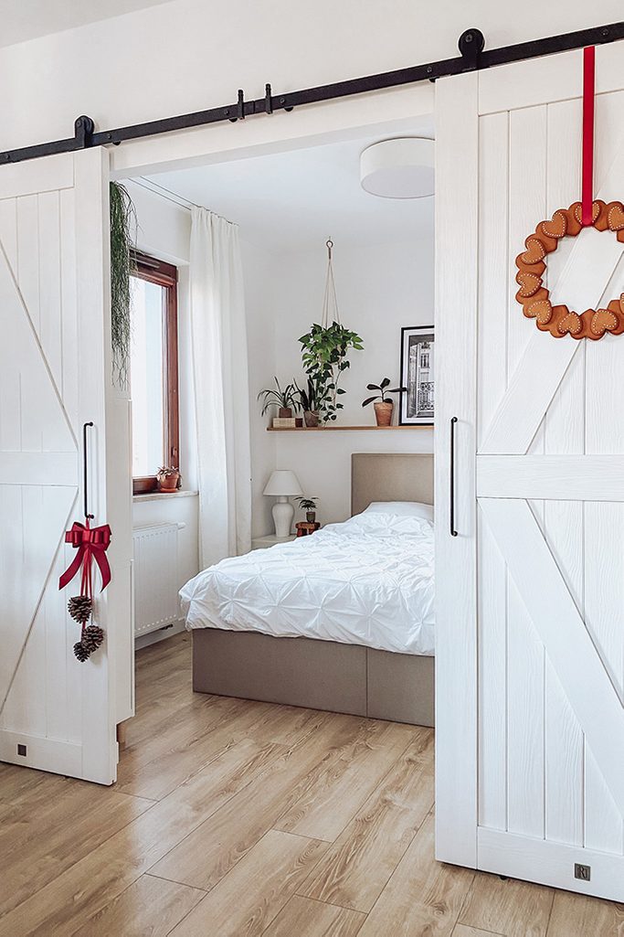 otwarte drzwi przesuwne ukazujące fragment sypialni urządzonej w bieli