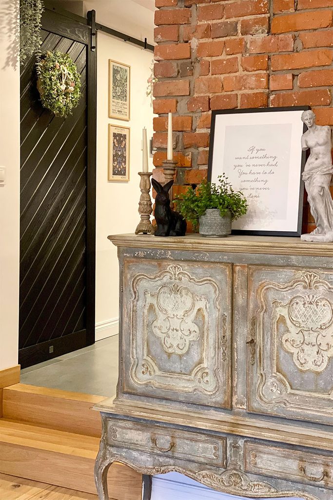 postarzana komoda w stylu rustykalnym przy ścianie z czerwonej cegły