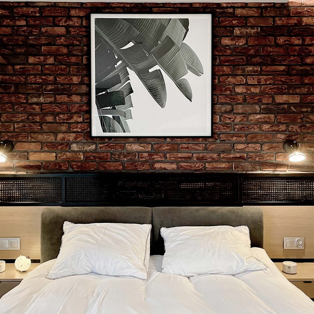 czarno biały plakat w ramce na ścianie z czerwonej cegły w loftowej sypialni