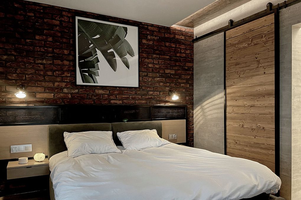 łóżko na tle ściany z czerwonej cegły w sypialni w stylu loftowym