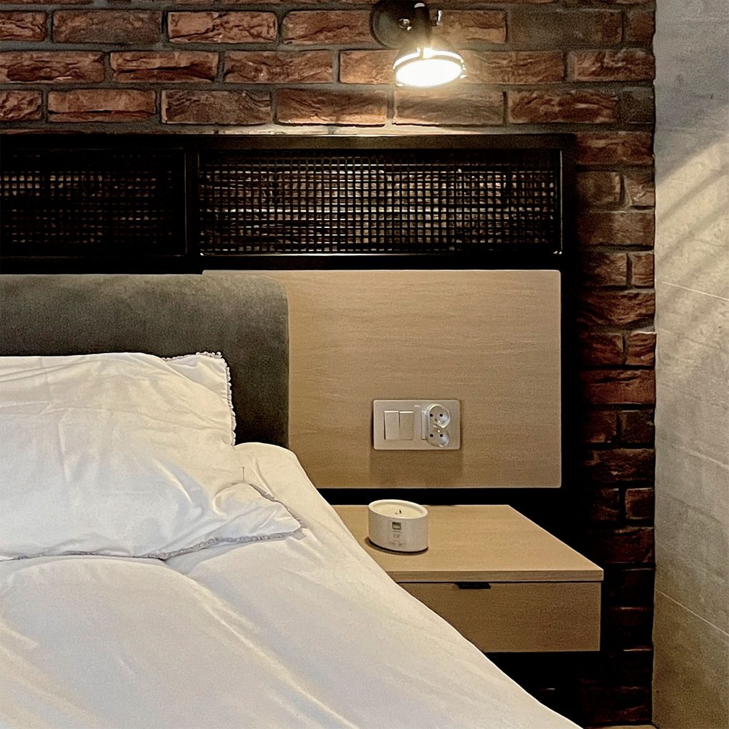 biała pościel na łóżku na tle ściany z czerwonej cegły w loftowej sypialni