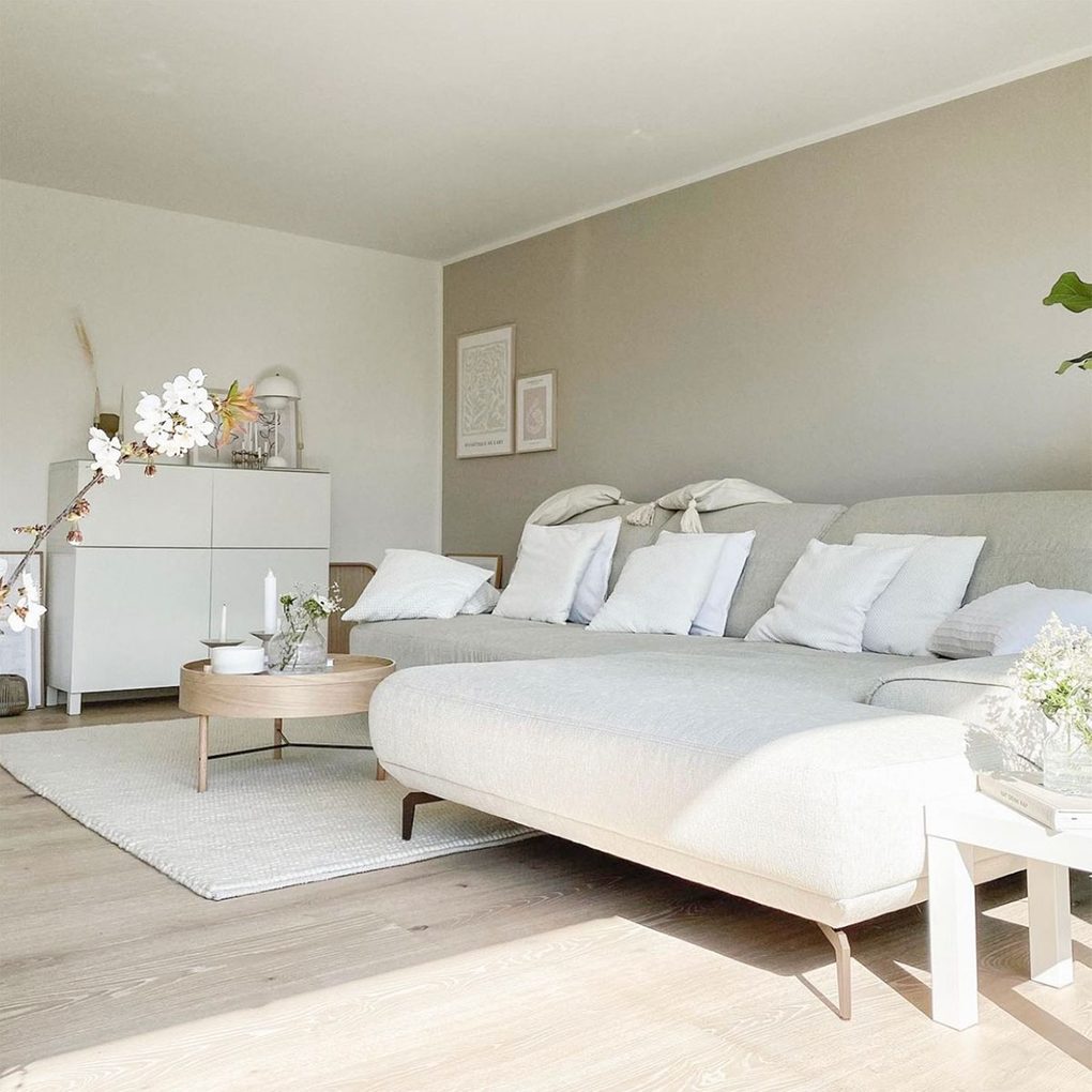 duża jasno beżowa sofa z białymi poduszkami w salonie