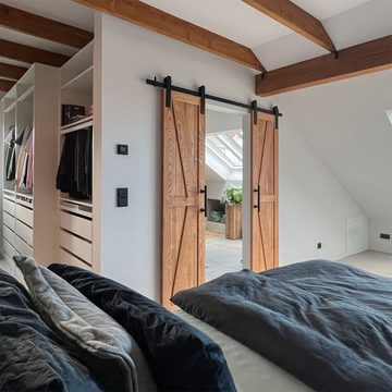 Wąskie drewniane drzwi przesuwne do łazienki w nowoczesnej sypialni na poddaszu