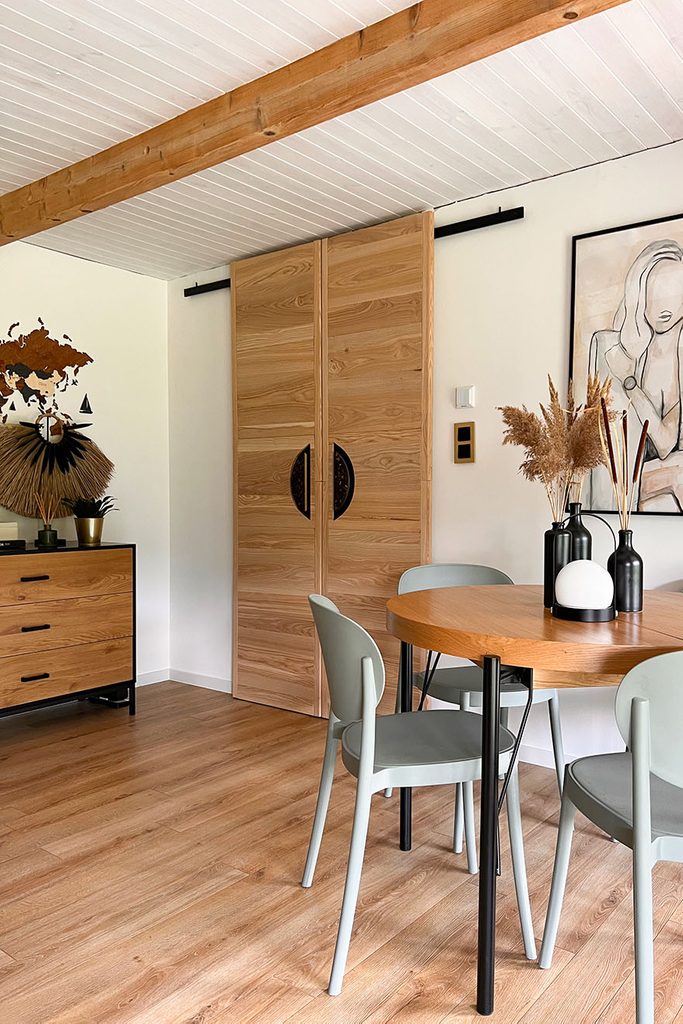 Drewniane designerskie drzwi przesuwne z czarnymi uchwytami w aranżacji pokoju gościnnego