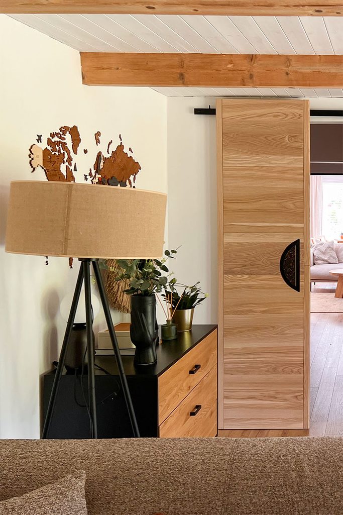 lampa stojąca z kloszem z juty stojąca obok drewnianej komody w czarnej obudowie