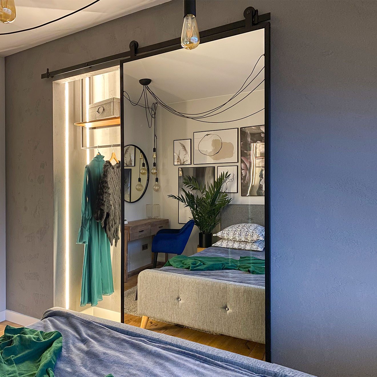 otwarte drzwi przesuwne z lustrem ukazujące małą garderobę we wnęce przy sypialni urządzonej w szarościach