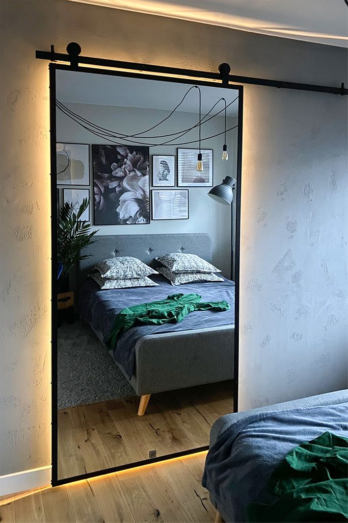 drzwi przesuwne z dużym lustrem w metalowej ramie zamykające garderobę we wnęce sypialni urządzonej w stylu loft