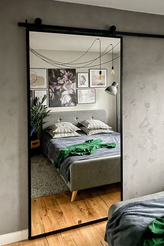 drzwi przesuwne z lustrem w metalowej ramie na szarej ścianie w sypialni urządzonej w stylu loft i kolorach szarości
