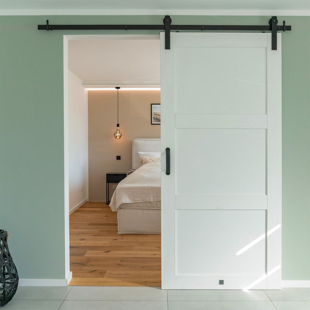Wejście do sypialni za nowoczesnymi drzwiami przesuwnymi w kolorze białym