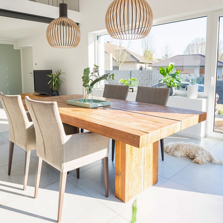 Masywny stół jadalniany, cztery tapicerowane beżowe krzesła oraz ażurowe lampy wiszące w aranżacji nowoczesnego salonu