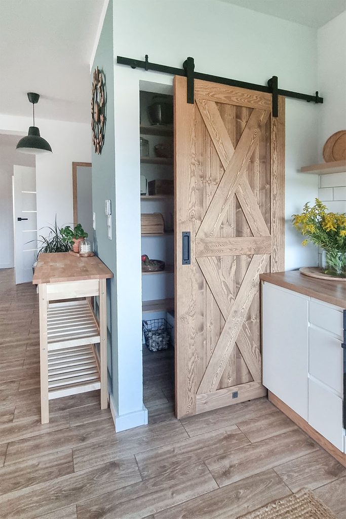 drewniane drzwi przesuwne do małej spiżarni w jasnej kuchni