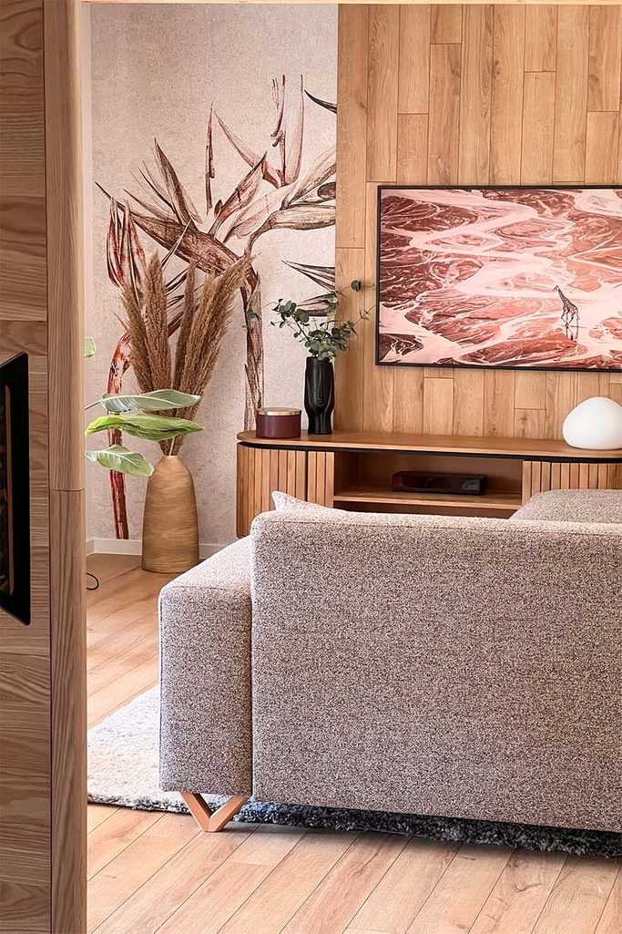 piaskowa sofa i ozdobna tapeta w pokoju gościnnym