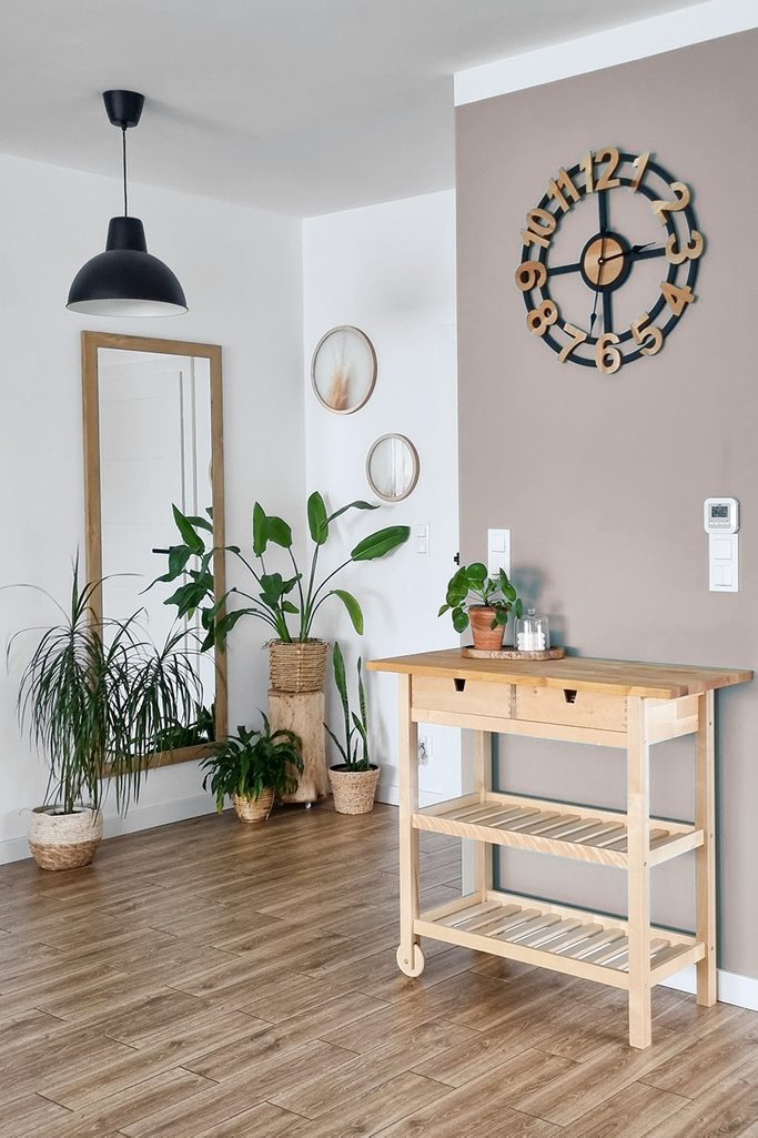 duży designerski zegar na szałwiowej ścianie nad drewnianym regałem w przedpokoju