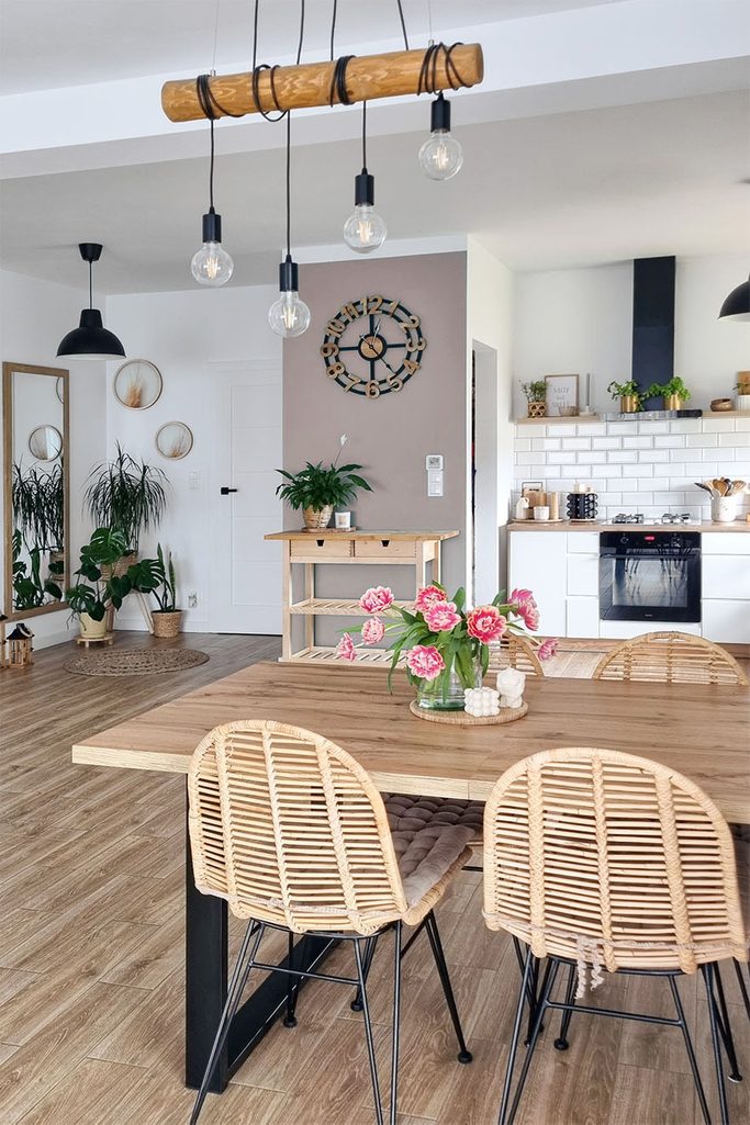 ażurowe krzesła w stół z drewnianym blatem w otwartej jadalni połączonej z kuchnią urządzoną w stylu skandynawskim