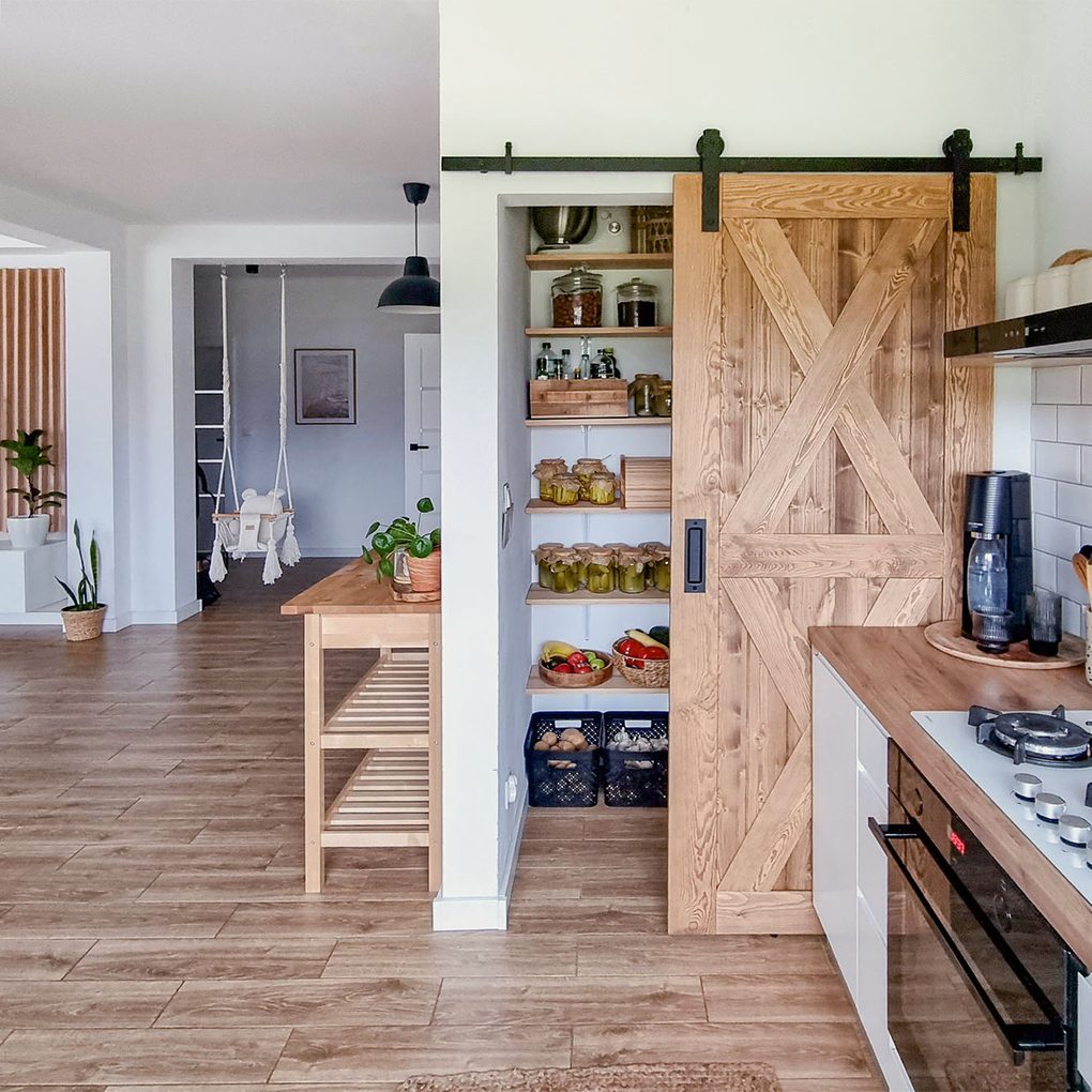 drewniane drzwi przesuwne do małej spiżarni w jasnej kuchni