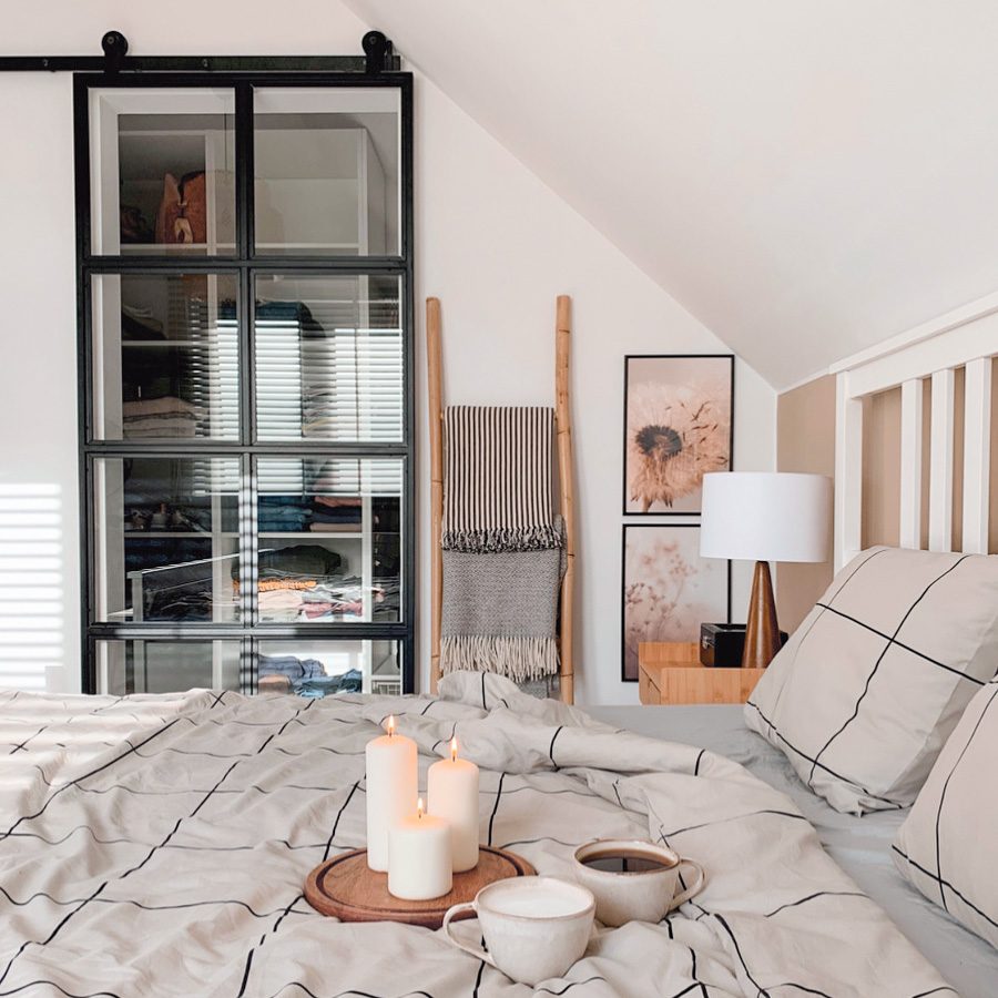 sypialnia na poddaszu z małą garderobą ukrytą za szklanymi drzwiami przesuwnymi