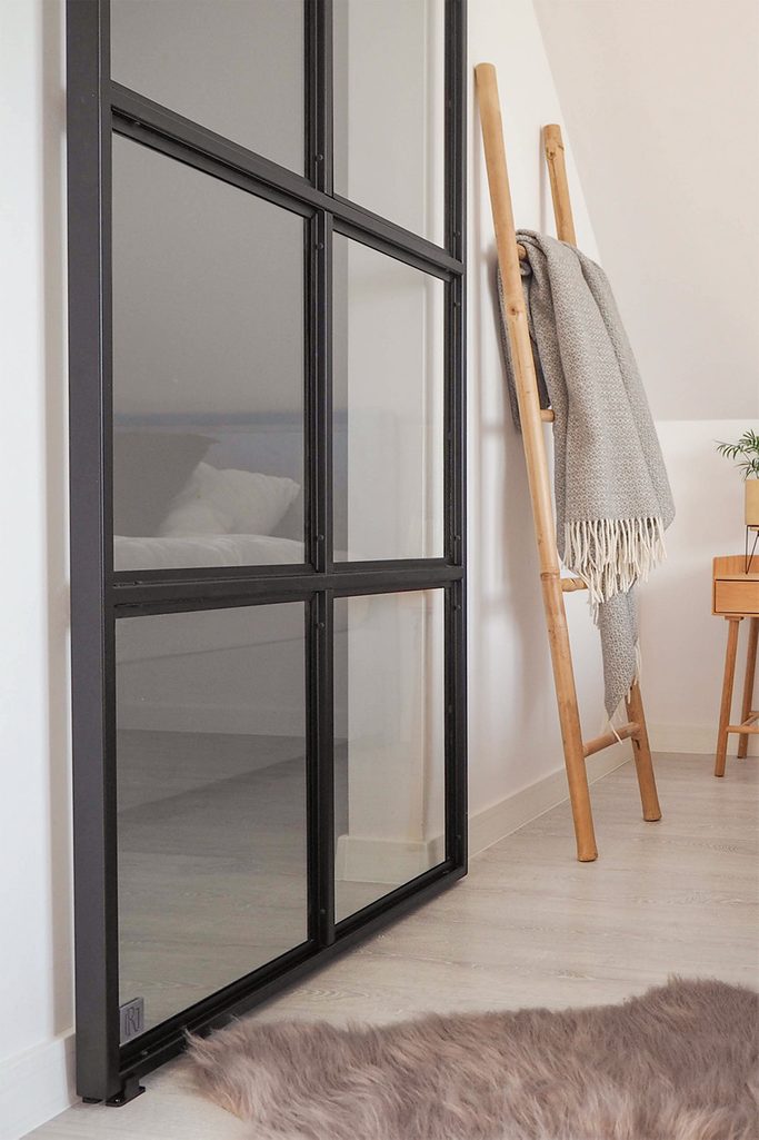 szklane drzwi przesuwne w czarnej metalowej ramie w wejściu do garderoby na poddaszu