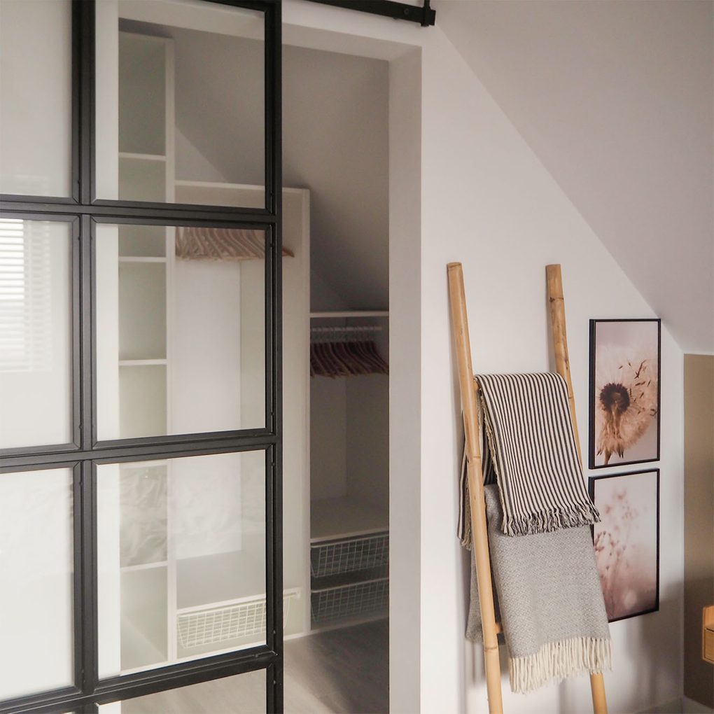 loftowe drzwi ze szkłem w metalowej ramie zamykające garderobę w małej sypialni na poddaszu