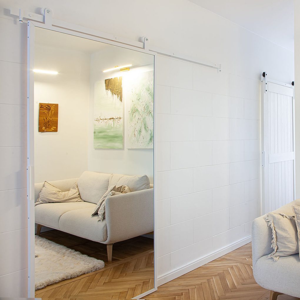 metalowe białe drzwi przesuwne z lustrem w salonie z jasno kremową sofą