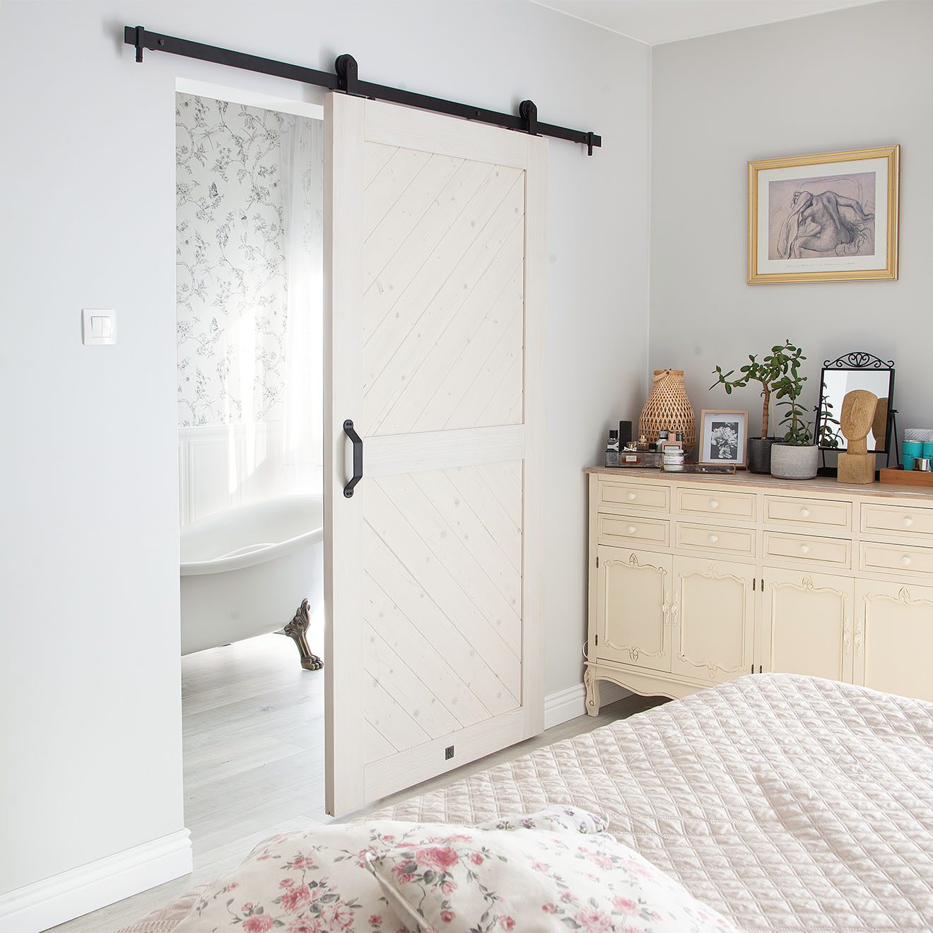 białe drewniane drzwi przesuwne oddzielające łazienkę od sypialni urządzonej w stylu prowansalskim
