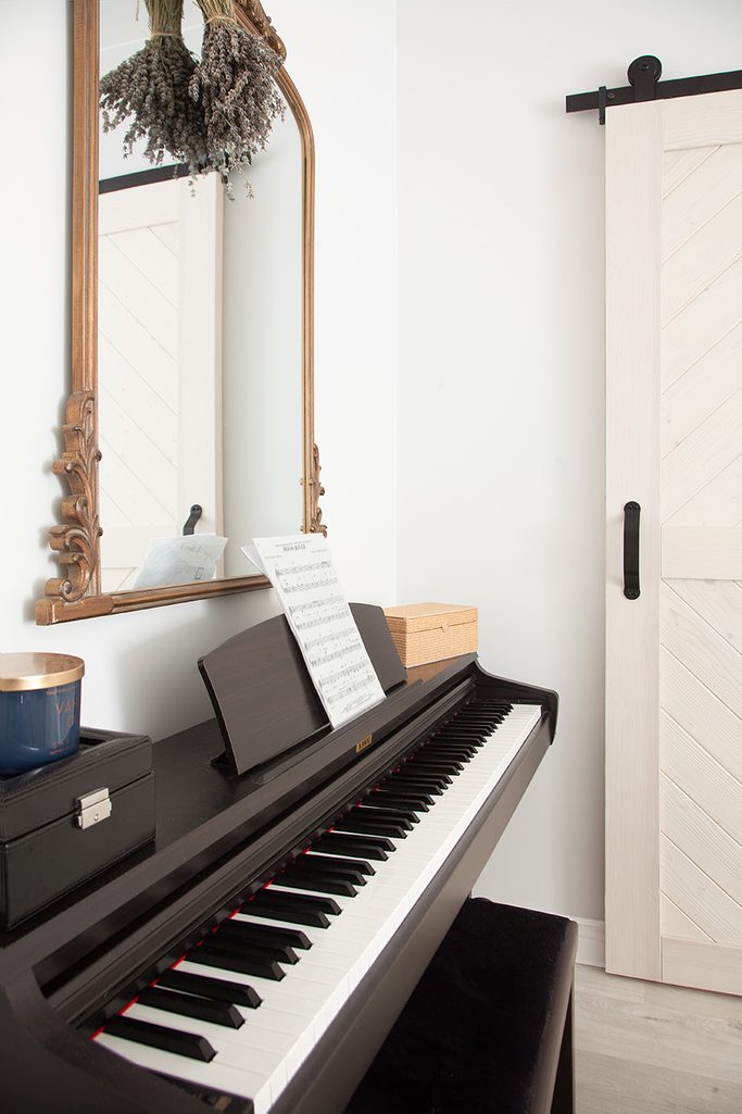 ozdobne lustro w drewnianej ramie na ścianie nad czarnym pianinem