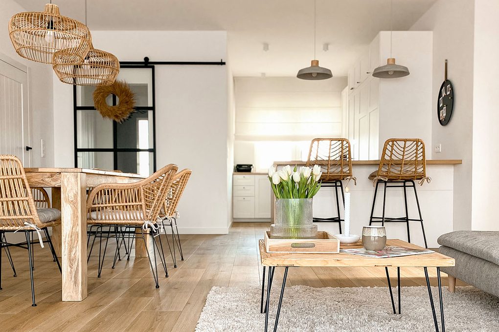 pokój dzienny z białymi ścianami i meblami z naturalnego drewna, rattanu i wikliniy